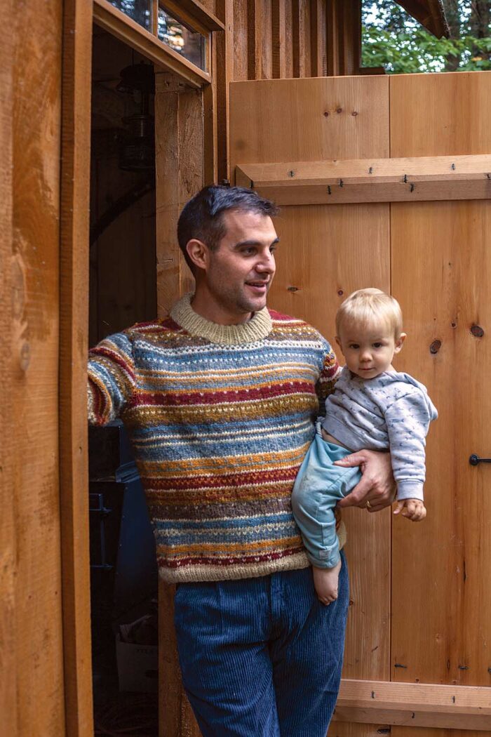 Brian Persico outside his timber frame shop holding his baby.