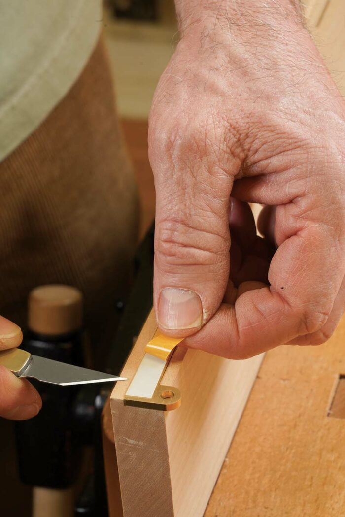 Locate the hinge leaf. Insert a hinge leaf into the setup block, and add a piece of double-stick tape to its face.